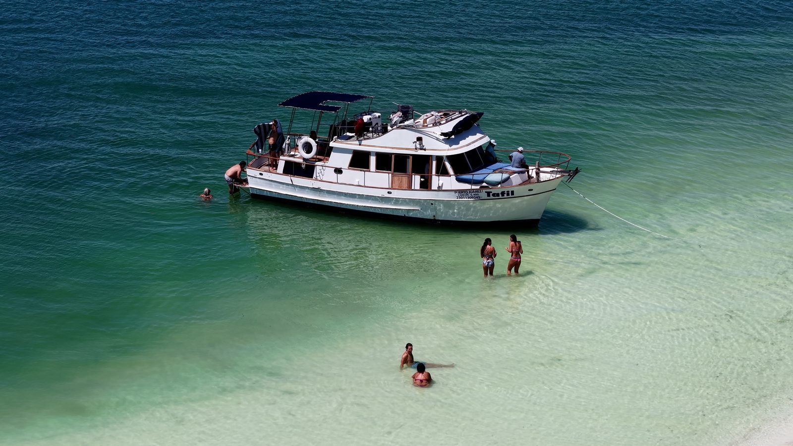 Guests swimming in the turquoise shallows beside the Tafil at Playa Conchitas
