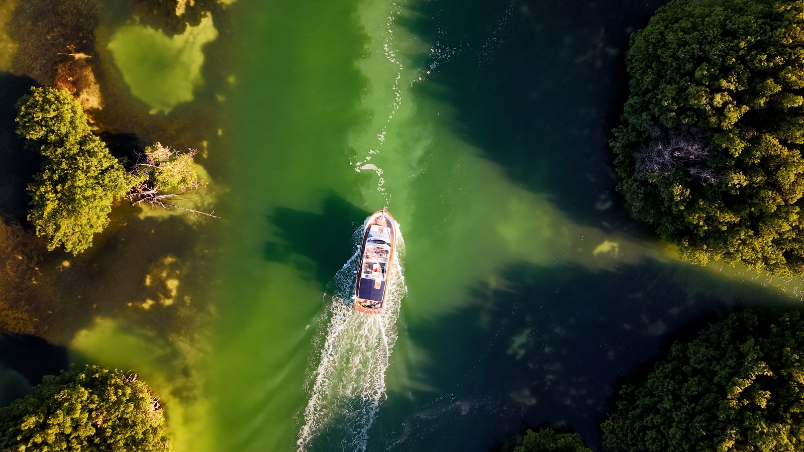 Overhead view of the Tafil leaving a wake across the green lagoon