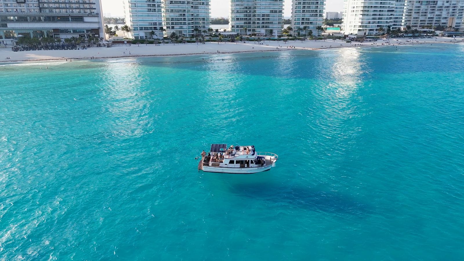Aerial view of the Tafil in turquoise water with the Cancún Hotel Zone towers along the shore