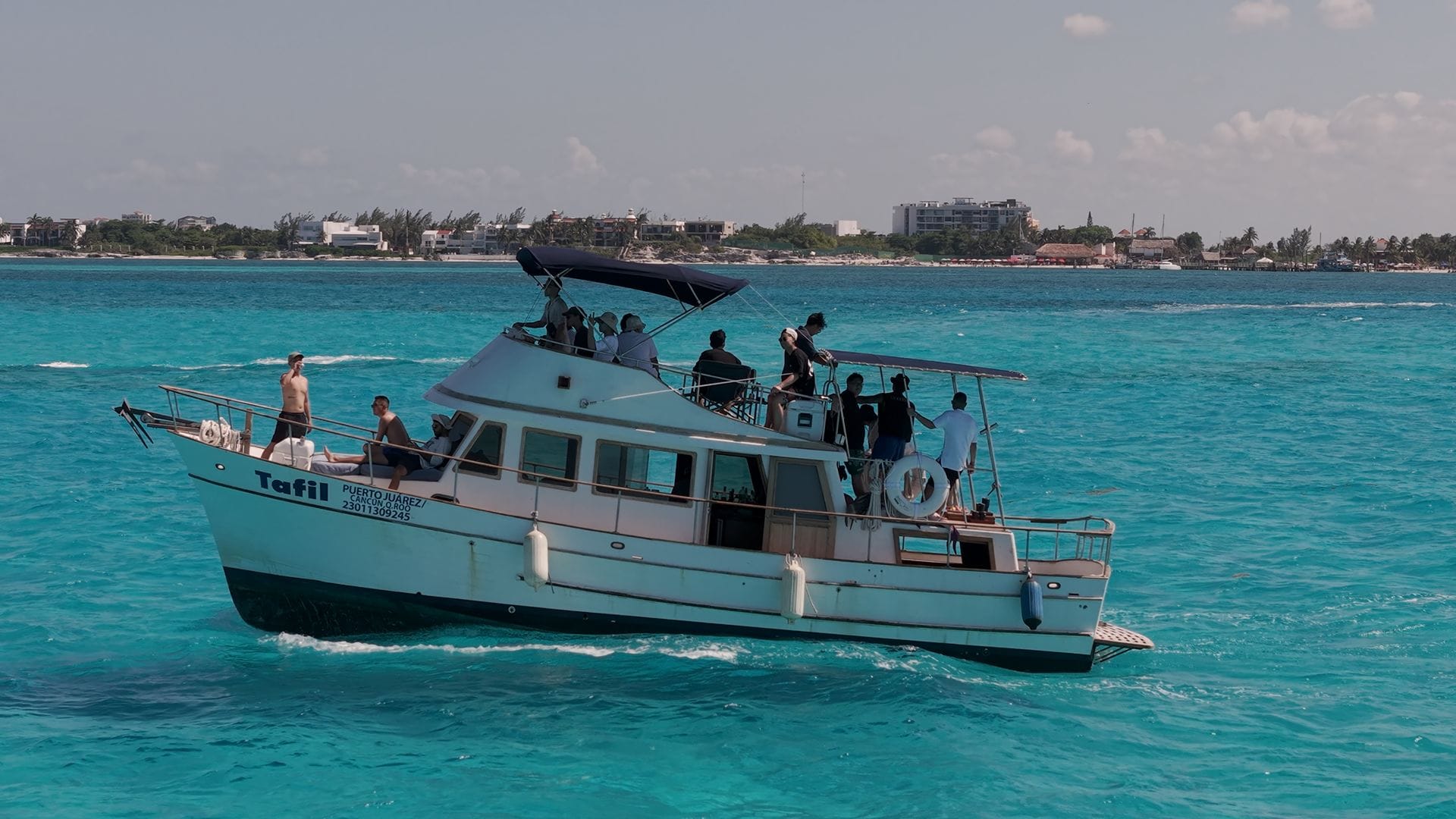 The Tafil under way with guests on the fly bridge and the Cancún skyline in the distance