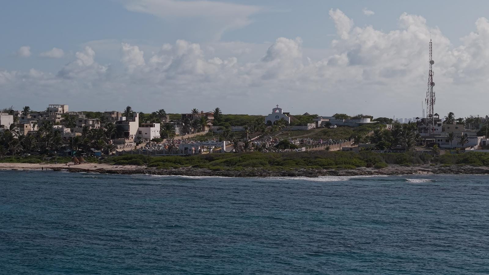 The east coast of Isla Mujeres seen from the sea with the lighthouse on the horizon