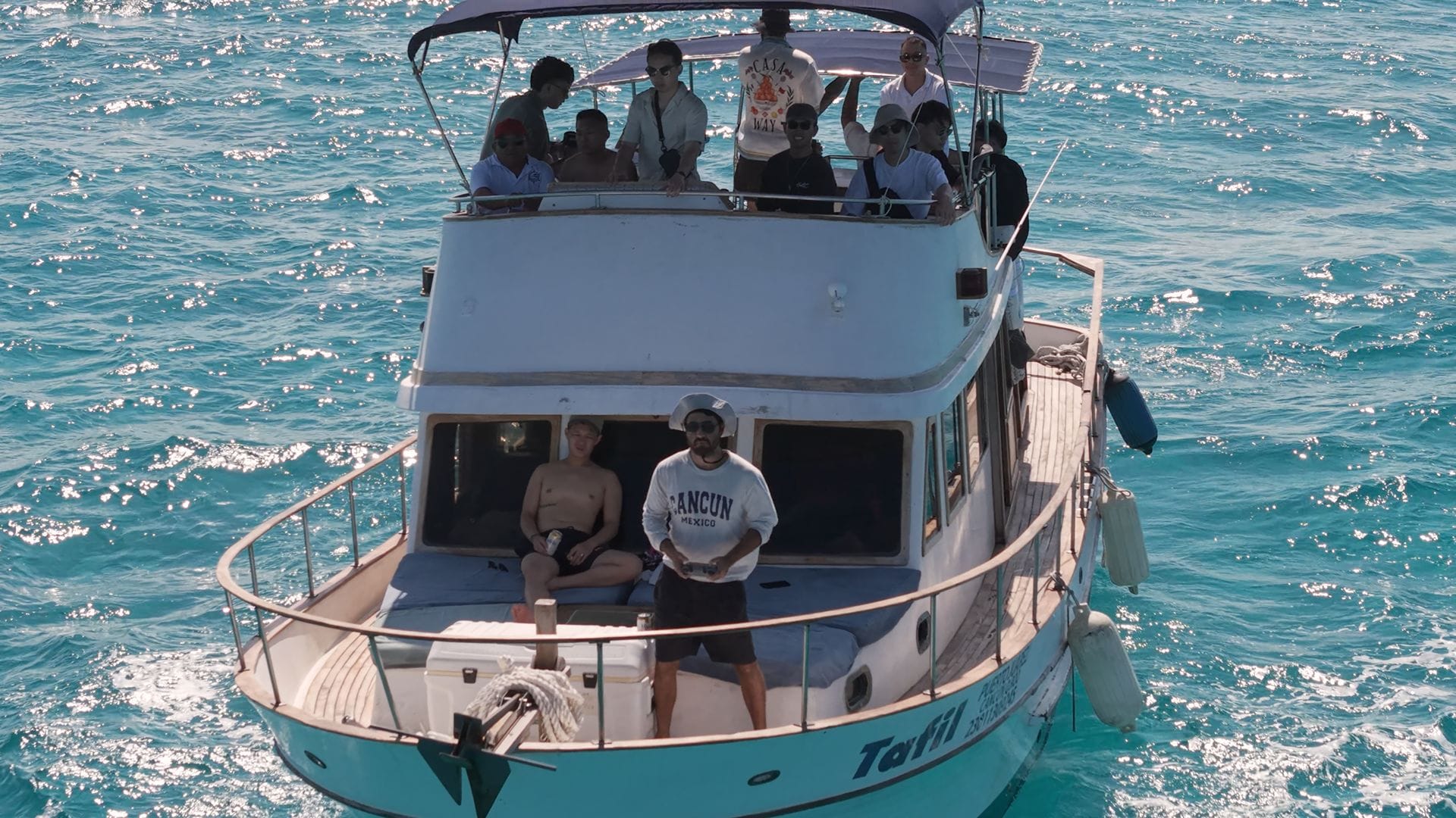 Guests waving from the bow and fly bridge of the Tafil in Cancún Bay