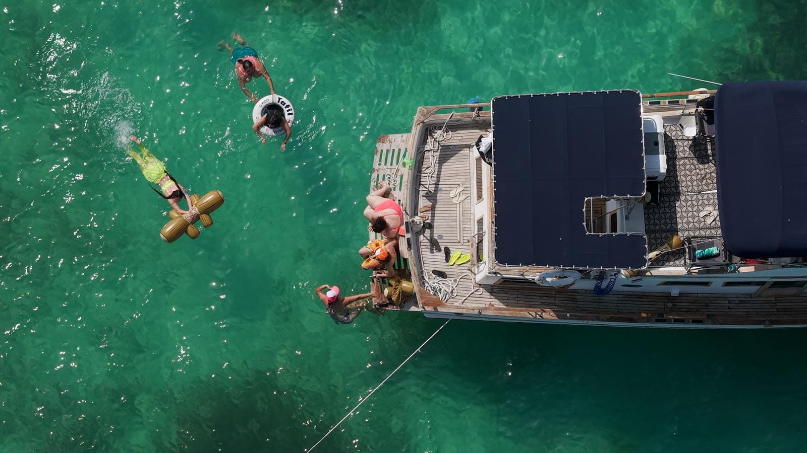 Top-down view of guests floating on inflatables beside the bow of the Tafil
