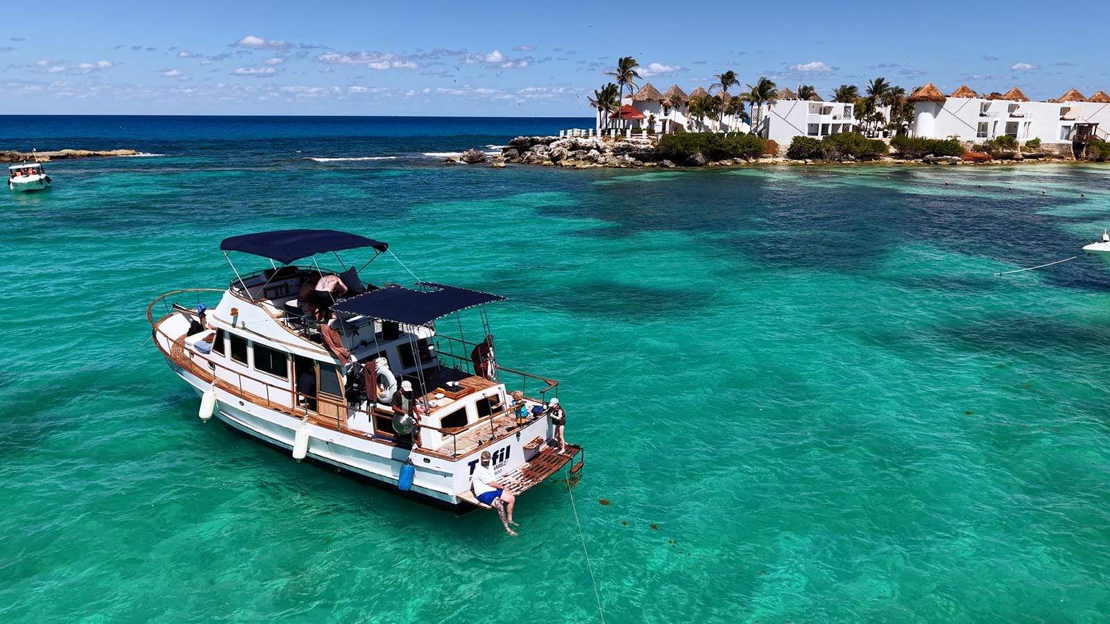 The Tafil anchored in turquoise water with the palm-lined point of Punta Norte behind