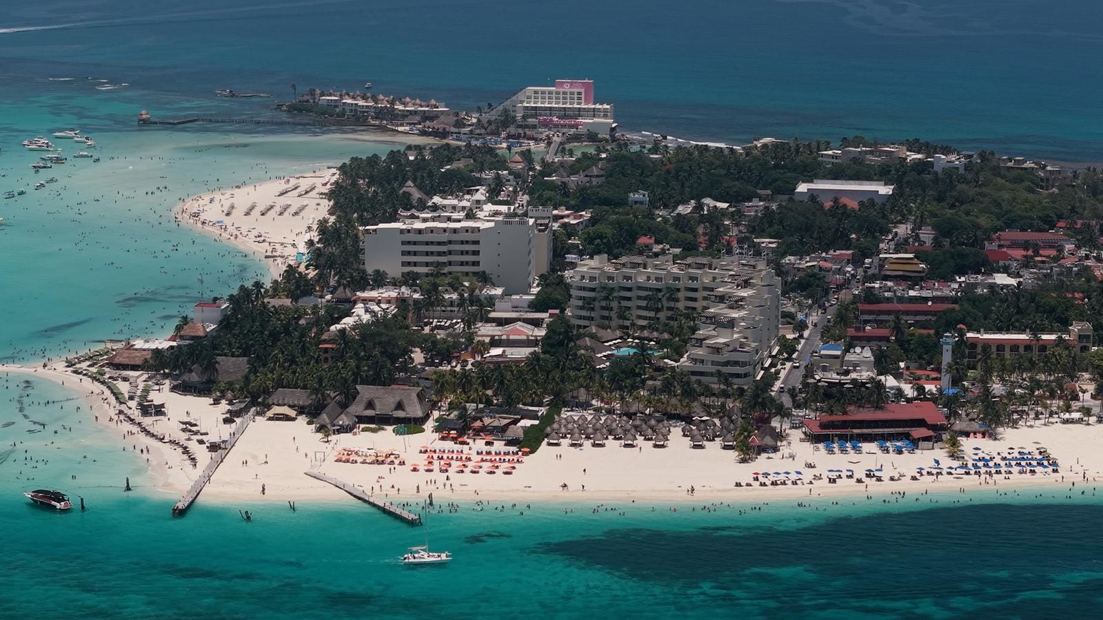 Aerial view of Playa Norte beach, palapas and the town of Isla Mujeres