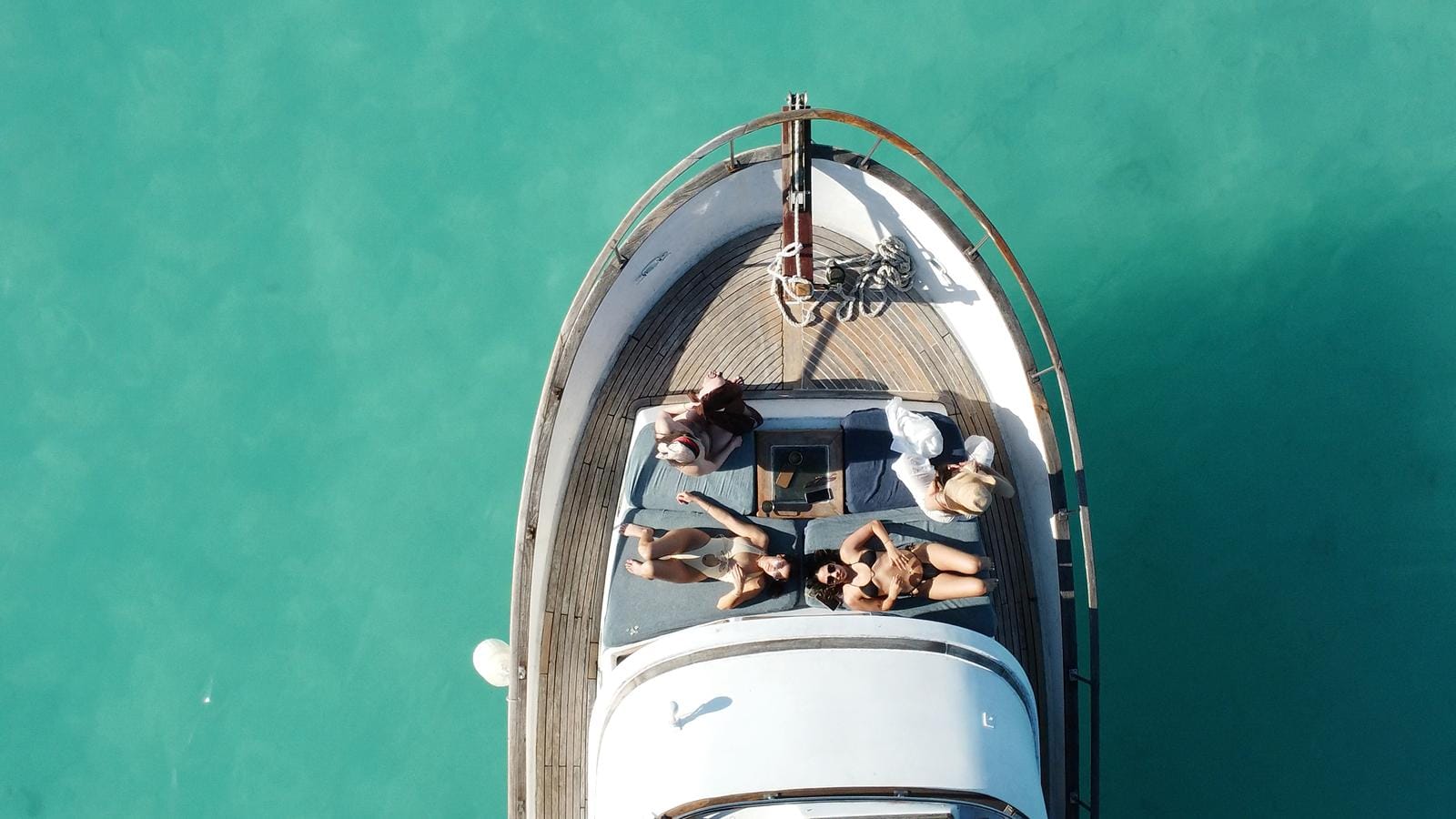 Top-down view of the bow of the Tafil with guests sunbathing over turquoise water