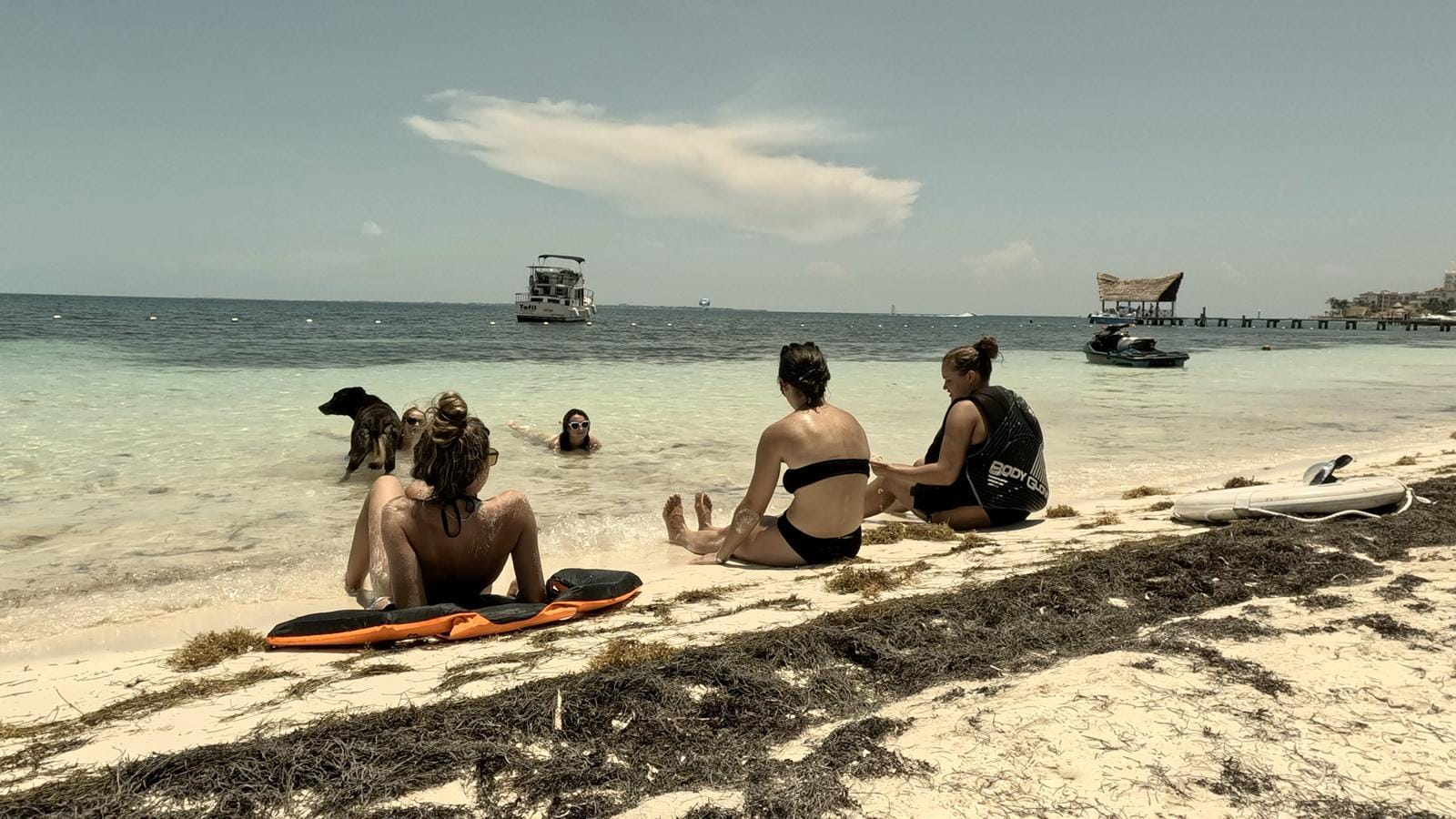 Guests relaxing on the sand at Presidente Beach with the Tafil anchored behind