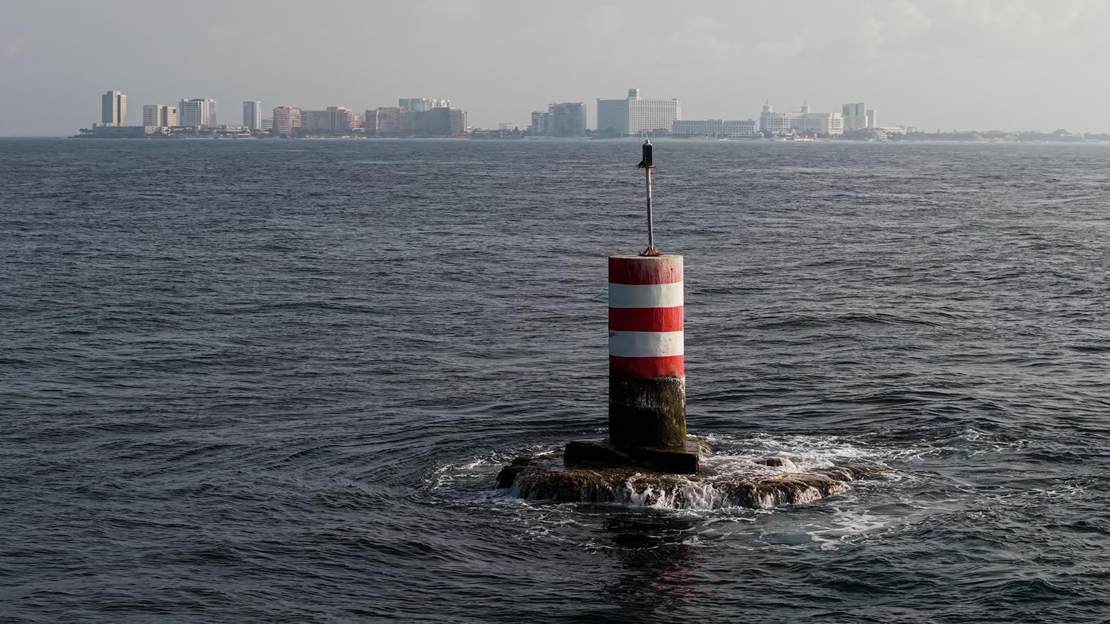 Navigation buoy off Isla Mujeres with the Cancún skyline on the horizon