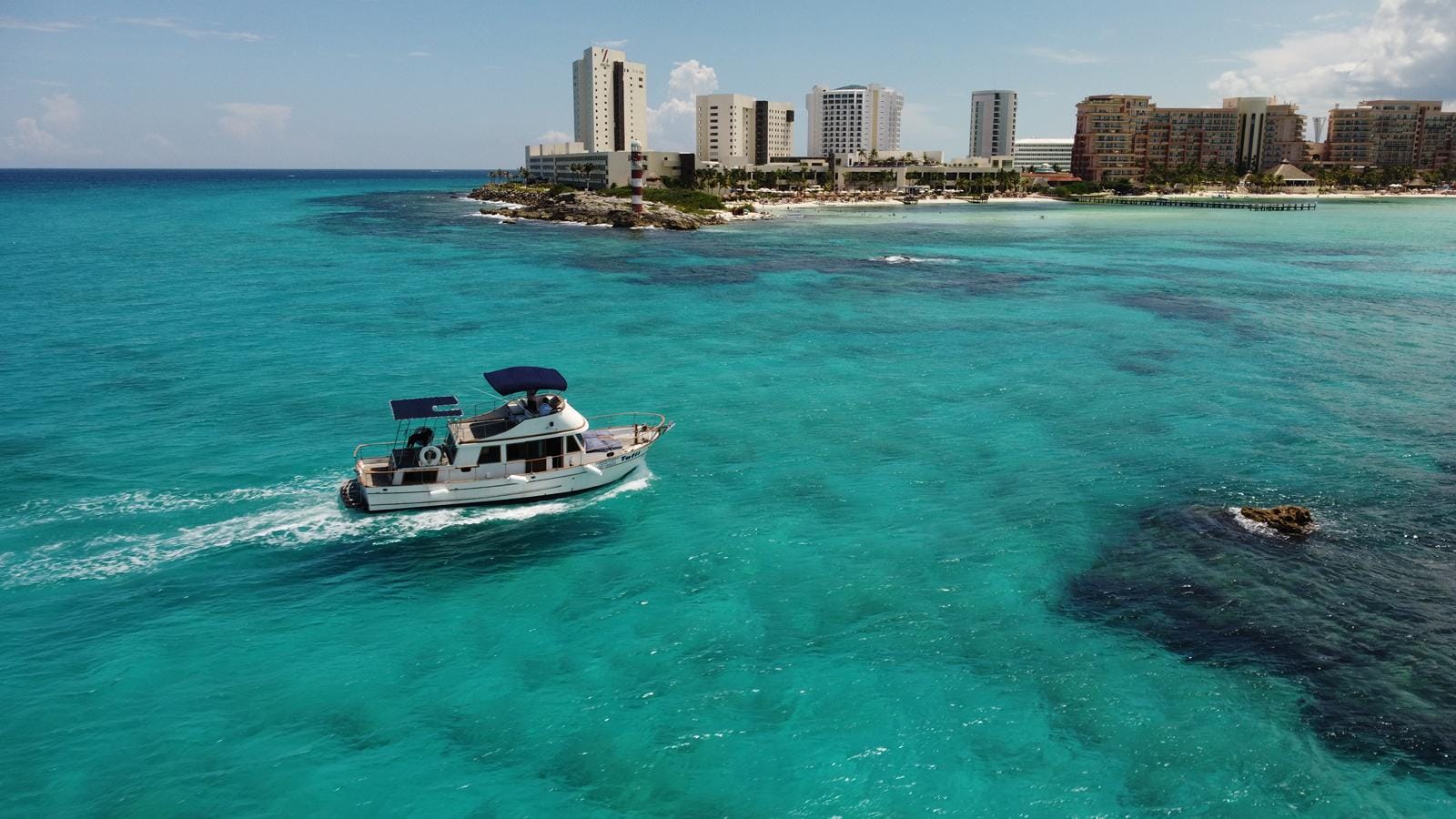 Aerial view of the Tafil in turquoise water with the Hotel Zone towers behind