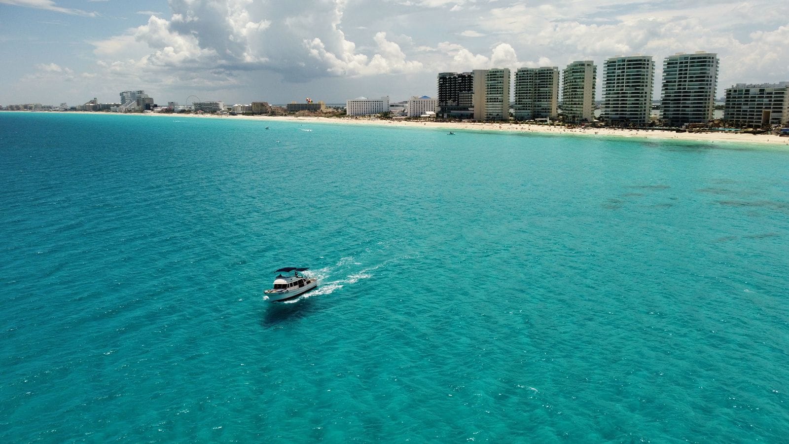 Aerial view of the Tafil in turquoise water with the Cancún Hotel Zone skyline behind